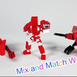 Puede incluir: Tres robots de juguete rojos y negros en diferentes poses, hechos de bloques de construcci&oacute;n. El texto "Mix and Match Weapons!" est&aacute; escrito en colores en la parte inferior de la imagen.