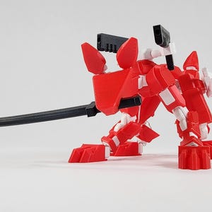 May include: A red and white articulated robot figure shaped like a quadrupedal animal. The figure features a black sword held in its mouth, a black rectangular component on its head, and a black weapon mounted on its back with white jointed limbs.