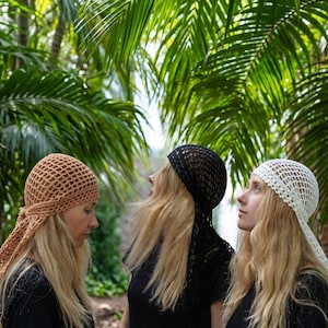 May include: Three crochet headscarves in tan, black, and white. Each headscarf features an open-knit mesh pattern with a tie-back design. The tan headscarf is on the left, the black headscarf is in the center, and the white headscarf is on the right.