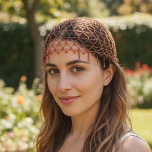 May include: A copper-colored beaded headpiece featuring a delicate, open-work lattice design that covers the crown of the head. The accessory is adorned with small, dangling beads along the lower edge, creating a fringe effect.