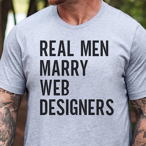 Könnte beinhalten: Ein hellgrau meliertes Kurzarm-T-Shirt mit dem schwarzen Text "REAL MEN MARRY WEB DESIGNERS", der in einer fetten, serifenlosen Schrift mittig auf der Brust aufgedruckt ist. Das Kleidungsstück hat einen klassischen Rundhalsausschnitt.
