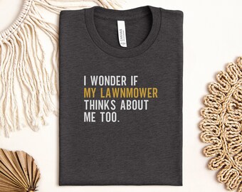 May include: A dark gray t-shirt with the text "I wonder if my lawnmower thinks about me too." printed in white. The text "lawnmower" is in gold.