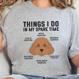 May include: A light gray t-shirt with the text "THINGS I DO IN MY SPARE TIME" above a cartoon Cavapoo dog illustration. The graphic lists activities like "Watch Cavapoos" and "Dream about Cavapoos."