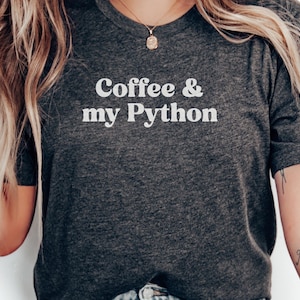 Peut inclure: T-shirt gris foncé avec l'inscription blanche "Coffee & my Python". Le t-shirt est à col rond et à manches courtes. Le texte est centré sur la poitrine.