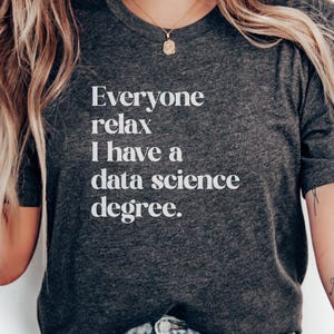 Può includere: T-shirt grigio scuro con la scritta bianca: "Everyone relax I have a data science degree". La maglietta ha un girocollo e maniche corte. Il design è umoristico e riguarda la data science.