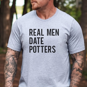 May include: A gray t-shirt with the text "REAL MEN DATE POTTERS" printed in black.