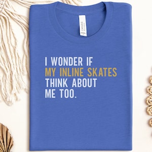 May include: A blue t-shirt with the text "I wonder if my inline skates think about me too." The text is in white and gold. The shirt is made of a soft material and has a crew neck.