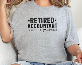 Könnte beinhalten: Hellgraues T-Shirt mit dem schwarzen Text "RETIRED ACCOUNTANT count it yourself". Der Text ist zentriert, mit "RETIRED" über "ACCOUNTANT". Das T-Shirt hat einen lässigen Stil.