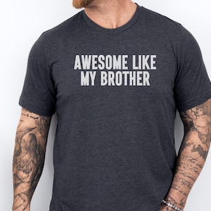 May include: A dark gray t-shirt with the text "Awesome Like My Brother" printed in white on the front.