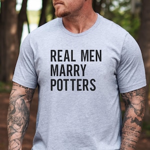 May include: A gray t-shirt with the text "REAL MEN MARRY POTTERS" printed in black.