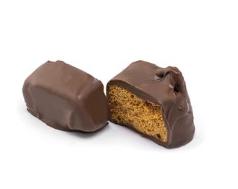 May include: A chocolate-covered honeycomb candy bar, broken in half to show the honeycomb inside. The candy bar is a light brown color and has a smooth chocolate coating.