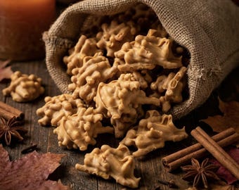 May include: A burlap sack spilling light brown, textured nut clusters onto a dark wooden surface. The scene includes scattered dried autumn leaves, whole cinnamon sticks, and star anise, with a warm candle glow in the background.