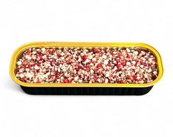 May include: A rectangular black and gold container filled with a mixture of small, irregularly shaped pieces. The pieces are primarily red and white, creating a textured surface. The container has a gold rim.