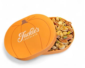 May include: An orange pumpkin-shaped box with the text "Jackie's Chocolate" in white script. The box is open, revealing a mix of nuts including cashews, walnuts, and pistachios. The box is on a white background.