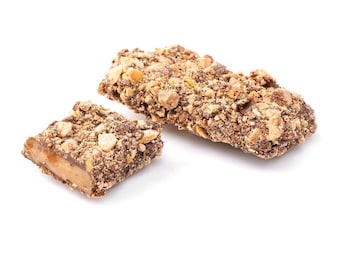 May include: Two pieces of chocolate toffee with peanuts, one broken in half, showing the caramel inside. The toffee is a light brown color and the peanuts are scattered throughout.