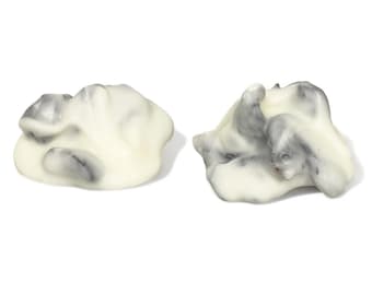 May include: Two abstract sculptures. Each sculpture has a white base with gray marbling. The forms are organic and cloud-like, with smooth, rounded surfaces. The sculptures are set against a white background.