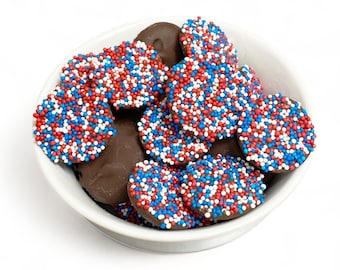 May include: A white bowl filled with chocolate covered pretzels with red, white, and blue sprinkles.