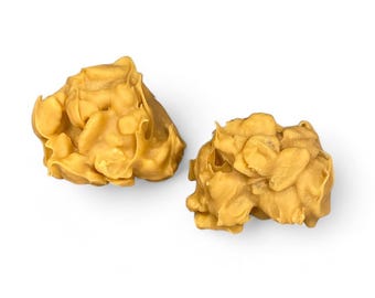 May include: Two golden peanut butter candies, each with a unique, irregular shape, are shown against a white background.