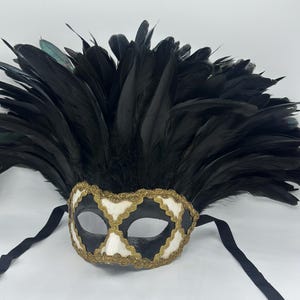 May include: A black masquerade mask with white and gold accents and a black feather headdress.