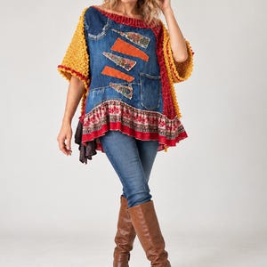 Puede incluir: Una blusa de texturas mixtas con un panel central de mezclilla azul con parches de tela naranja, un dobladillo con estampado floral rojo y blanco, y mangas de punto amarillo mostaza. Se combina con pantalones de mezclilla azules y botas altas de cuero marrón.
