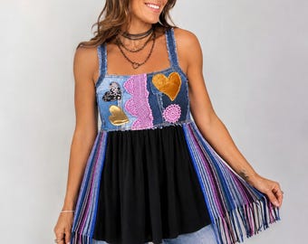 May include: A sleeveless top featuring a denim bodice with frayed edges, adorned with gold and black heart patches and a pink lace trim. The lower section is a solid black fabric with long, multicolored fringe panels in shades of blue and purple.
