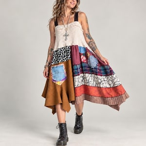 May include: A sleeveless patchwork dress featuring a cream-colored ribbed bodice, a brown suede-like panel with a denim pocket, and a multi-patterned skirt with floral, plaid, and solid fabric sections in shades of red, blue, and white.