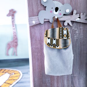 Peut inclure: Un crochet en bois en forme de koala gris avec un sac à dos à motifs gris et blancs suspendu. Le crochet est fixé à une branche en bois avec des boutons blancs.