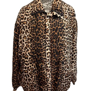 May include: A leopard print jacket with a black zipper and collar. The jacket is brown, black, and tan with a full-length zipper and a high collar. The jacket is displayed on a mannequin.
