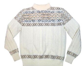 May include: A cream-colored long-sleeve sweater featuring a mock neck collar and a textured cable knit pattern. The garment is accented with a horizontal band across the chest and cuffs displaying a geometric pattern in shades of gray and tan.