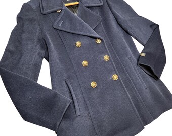 May include: A navy blue double-breasted coat with gold-colored buttons. The coat has a classic design with a notched collar and two front pockets. The coat is hanging on a wooden hanger.