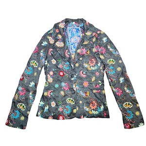 May include: A black blazer with a floral pattern in shades of pink, blue, green, and yellow. The blazer has a button closure and long sleeves.