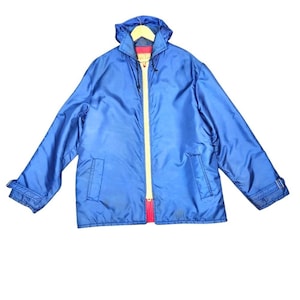 May include: A bright blue jacket with a hood, a yellow zipper, and red accents. The jacket has two front pockets and adjustable cuffs. The jacket is made of a shiny, water-resistant material.