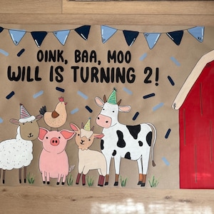 May include: A hand-painted birthday banner with a farm animal theme. The banner features a red barn, a cow, a sheep, a pig, a goat, and a chicken. The text "OINK, BAA, MOO WILL IS TURNING 2!" is written across the top.