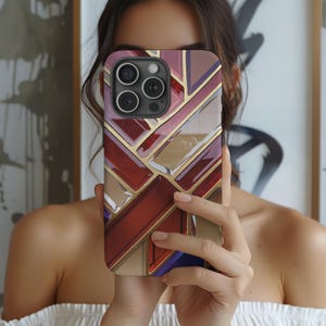 Könnte beinhalten: Eine geometrische Handyhülle in Rot, Gold und Blau mit einem Buntglasdesign. Die Hülle ist für ein Smartphone mit einer Dreifachkamera konzipiert.