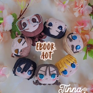 Puede incluir: Una colección de cabezas de personajes de ganchillo hechas a mano, con varios colores y detalles. El texto "EBOOK AOT" es visible, junto con la firma del creador. Los personajes están dispuestos en un patrón circular, rodeados de flores rosas.