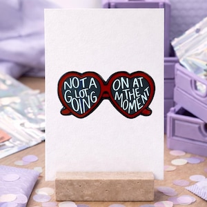 Taylor Swift inspirierter Pin - "Not a Lot Going on at the Moment" - Rote Herzbrille mit Weißer Schrift - Für Taylor Swift Fans/Swifties