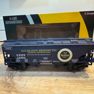 Könnte beinhalten: Ein dunkelblauer O-Line Reproductions Modellzugwagen von Old Reading Brewery Inc. Das Modell trägt den Text "Reading Premium Beer" und "O.R.B.X 18864". Eine kleine Figur ist an der Seite des Wagens befestigt.