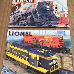 May include: Two Lionel Legendary Trains catalogues. The top catalogue features a black steam engine with the number 3447. The bottom catalogue shows a blue and yellow Virginian electric train, number 2329, with an orange train in the background.