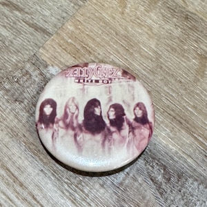 May include: A circular button with a sepia-toned image of the band Zella & The Glez. The button features the band's name and the text "White Boy". The image shows the band members in a vintage style.