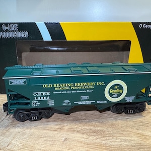 Könnte beinhalten: Ein dunkelgrüner Modell-Zugwagen der Spur O von Old Reading Brewery Inc. Das Modell zeigt den Namen und das Logo der Brauerei sowie den Text "Brewed with clear Blue Mountain Water". Der Wagen steht auf einer Holzoberfläche.