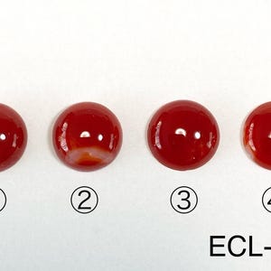 Op de afbeelding: Vier ronde, rode cabochon edelstenen met een licht wit swirl-patroon. De edelstenen zijn genummerd van 1 tot 4. De tekst "ECL-011" staat onder de edelstenen.