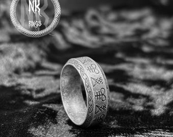 May include: A silver ring with etched symbols and a decorative border. The ring is set against a dark, textured background. The logo "NK RINGS" is displayed above the ring in a circular design.