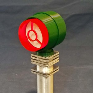 May include: A green and red microphone with a silver stand. The microphone has a round, red grill with a white center.