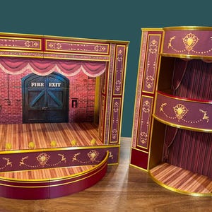 May include: Two miniature theater stage models. The stage is burgundy and gold with a wooden floor and a brick backdrop. The stage has a proscenium arch and a curved front. The second model is a multi-level box with burgundy and gold accents.