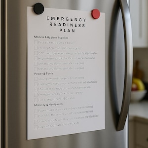May include: A white paper with an "EMERGENCY READINESS PLAN" is attached to a stainless steel refrigerator with black and red magnets. The plan lists medical, hygiene, power, and mobility supplies for emergency preparedness.
