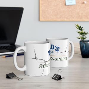 May include: Two white ceramic mugs with a cracked design. The mug on the right has the text "World's Best Structural Engineer" in blue and green text.