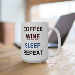 May include: White ceramic coffee mug with the text "COFFEE WINE SLEEP REPEAT" printed on it. The words "COFFEE" and "REPEAT" are in black, "WINE" is in maroon, and "SLEEP" is in blue.