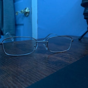 May include: Silver rectangular-framed eyeglasses with clear lenses.