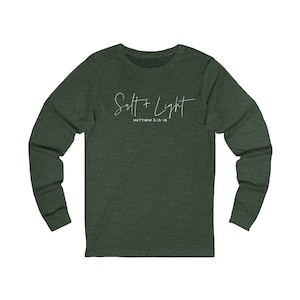 May include: Dark green long-sleeve shirt with the text "Salt + Light" and the scripture reference Matthew 5:13-16 in white script. The shirt has a crew neck and long sleeves.
