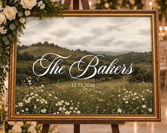Puede incluir: Un letrero de bienvenida de boda rectangular en un marco dorado con una impresión de paisaje de colinas verdes y un prado de flores. El texto "The Bakers" está escrito en letra cursiva blanca, seguido de la fecha "12.13.2026" en una fuente sans-serif.